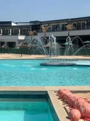 a swimming pool with a fountain in front of a building at The Blyde Crystal Lagoons in Pretoria
