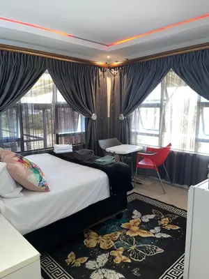 a bedroom with a bed and a table and chairs at Sbarba guesthouse in Ga-Kgapane