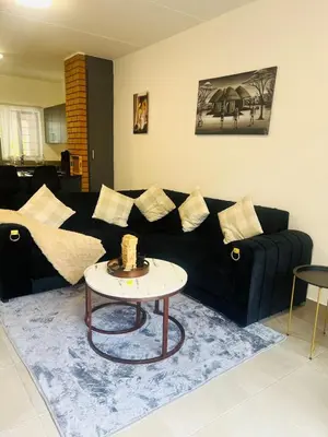 a living room with a black couch and a table at 2 bedroom signature luxury apartment in Midrand