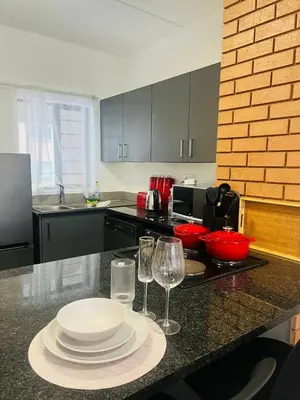 a kitchen with a table with plates and wine glasses at 2 bedroom signature luxury apartment in Midrand