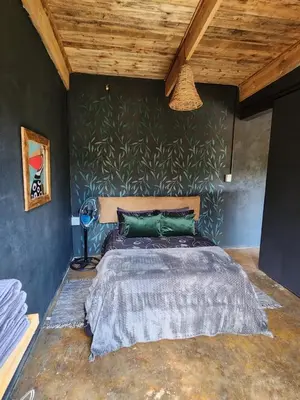 a bedroom with a bed with a green wall at Hartbeest Bush Stay #2 in Hartbeespoort