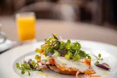 a white plate with a piece of pizza with greens on it at Kapama Buffalo Camp in Kapama Private Game Reserve