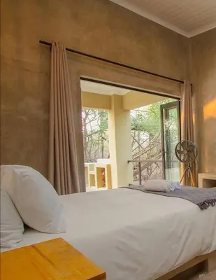 a bedroom with a large white bed with a window at Makrugu Forest in Marloth Park