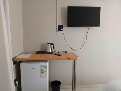 a table with a television on top of a refrigerator at Joyful Home Bela-Bela in Bela-Bela