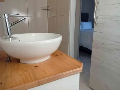 a bathroom with a white bowl sink on a wooden table at Joyful Home Bela-Bela in Bela-Bela
