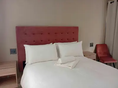 a bedroom with a white bed with a red headboard at Joyful Home Bela-Bela in Bela-Bela