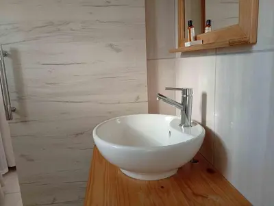 a bathroom with a white bowl sink on a wooden floor at Joyful Home Bela-Bela in Bela-Bela