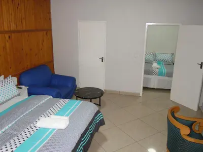 a bedroom with a bed and a chair and a mirror at Daeka Guesthouse in Kempton Park