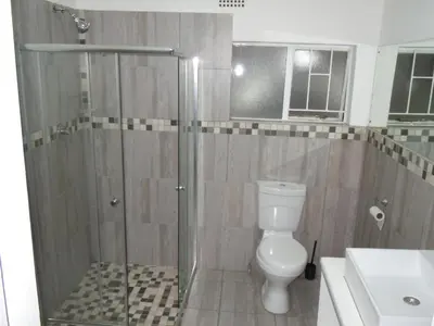 a bathroom with a shower with a toilet and a sink at Daeka Guesthouse in Kempton Park