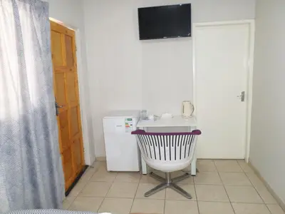 a small kitchen with a chair and a sink at Daeka Guesthouse in Kempton Park