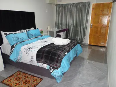 a bedroom with a large bed with blue pillows at Daeka Guesthouse in Kempton Park