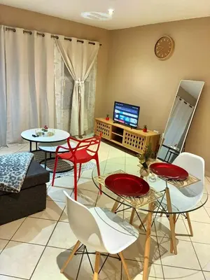 a living room with tables and chairs and a television at Apartment with Breathtakingly Beautiful Lake Views in Pretoria