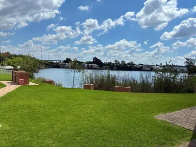 a view of a river from a park with green grass at Apartment with Breathtakingly Beautiful Lake Views in Pretoria