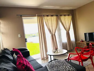 a living room with a couch and a table and a window at Apartment with Breathtakingly Beautiful Lake Views in Pretoria