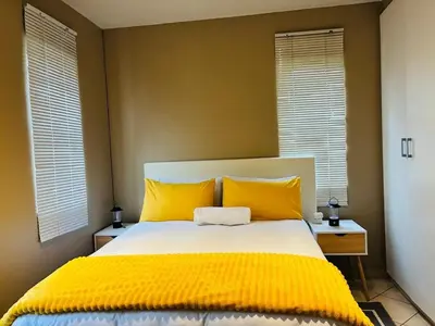 a bedroom with a bed with yellow pillows and windows at Apartment with Breathtakingly Beautiful Lake Views in Pretoria