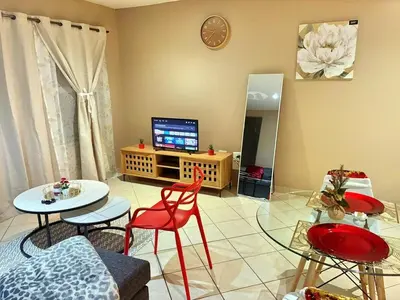 a living room with a tv and a table and chairs at Apartment with Breathtakingly Beautiful Lake Views in Pretoria