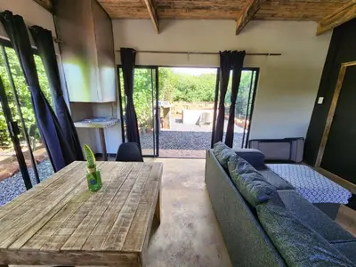 a living room with a couch and a wooden table at Hartbeest Bush Stay #29 in Hartbeespoort
