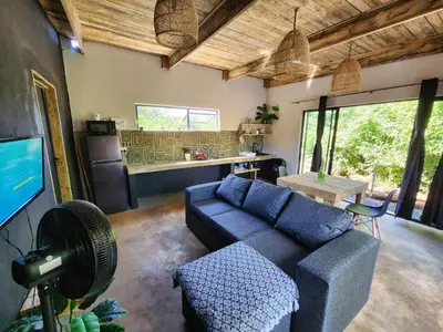 a living room with a blue couch and a kitchen at Hartbeest Bush Stay #29 in Hartbeespoort