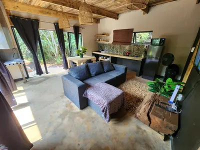 a living room with a blue couch and a kitchen at Hartbeest Bush Stay #27 in Hartbeespoort