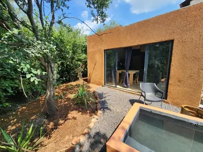 a house with a window and a chair in the yard at Hartbeest Bush Stay #27 in Hartbeespoort
