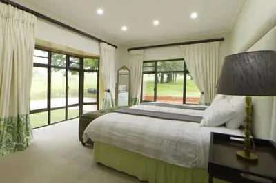 a bedroom with a large bed and large windows at Elgin Farm Dullstroom in Dullstroom