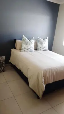 a large bed with white sheets and pillows on it at Tshepang Modern Suites Secunda in Secunda