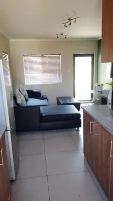 a living room with a black couch in a kitchen at Tshepang Modern Suites Secunda in Secunda