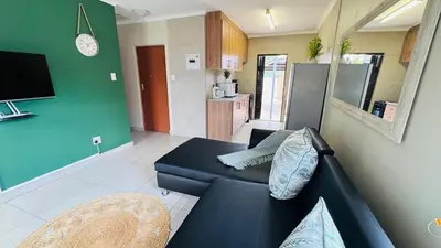 a living room with a blue couch and a kitchen at Tshepang Modern Suites Secunda in Secunda