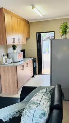 a kitchen with a couch and a refrigerator at Tshepang Modern Suites Secunda in Secunda