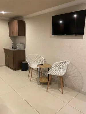a kitchen with two chairs and a table and a television at Village Walk Guesthouse
