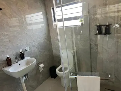 a bathroom with a sink and a toilet and a shower at Village Walk Guesthouse
