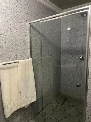a shower with a glass shower stall with a towel at Village Walk Guesthouse