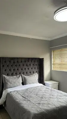 a bedroom with a large bed with a large headboard at Garden Flat to rent in Pretoria