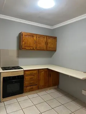 a kitchen with wooden cabinets and a counter top at Garden Flat to rent in Pretoria