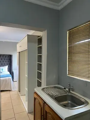 a kitchen with a sink and a bedroom with a bed at Garden Flat to rent in Pretoria