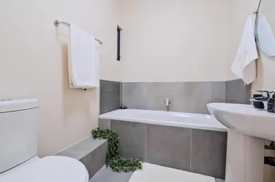 a bathroom with a toilet and a sink and a bath tub at Nat's Villa 2 in Midrand