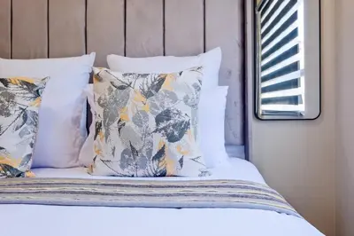 a bed with white sheets and pillows and a window at Nat's Villa 2 in Midrand