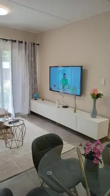 a living room with a flat screen tv on a wall at Nat's Villa 2 in Midrand