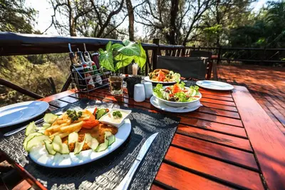 a wooden table with a plate of food on it at Grand Kruger Lodge and Spa in Marloth Park