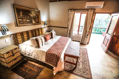 a bedroom with a bed and a table and a window at Grand Kruger Lodge and Spa in Marloth Park