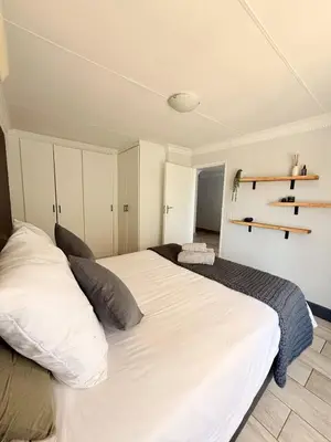 a bedroom with a large white bed and shelves at Casa Della Monument Park in Pretoria