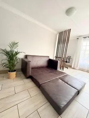 a leather couch in a living room with a plant at Casa Della Monument Park in Pretoria