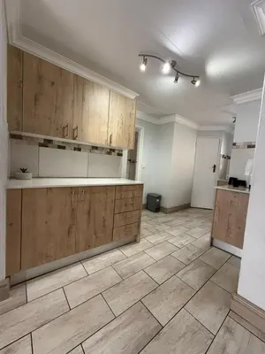 an empty kitchen with wooden cabinets and a tile floor at Casa Della Monument Park in Pretoria