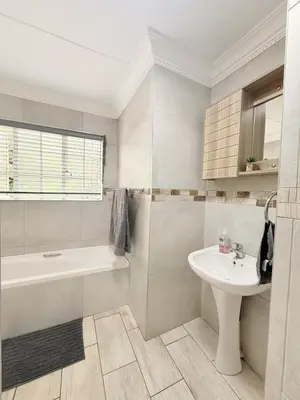 a white bathroom with a sink and a tub and a toilet at Casa Della Monument Park in Pretoria