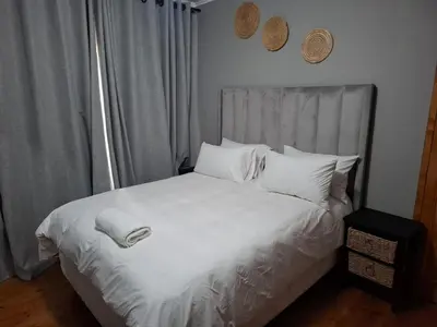 a bed with white sheets and pillows in a bedroom at Junior's inn place in Hartbeespoort