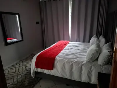 a bedroom with a bed with a red blanket on it at Junior's inn place in Hartbeespoort