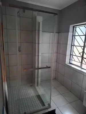 a shower with a glass door in a bathroom at Junior's inn place in Hartbeespoort