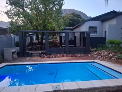 a pool with a pergola next to a house at Junior's inn place in Hartbeespoort