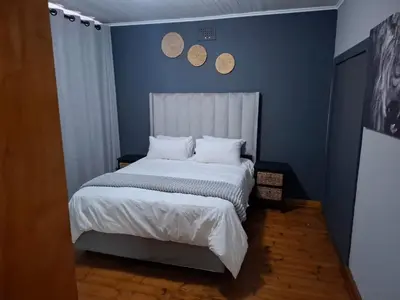 a bedroom with a white bed with blue walls at Junior's inn place in Hartbeespoort