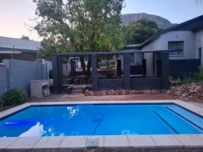 a swimming pool in a yard with a house at Junior's inn place in Hartbeespoort
